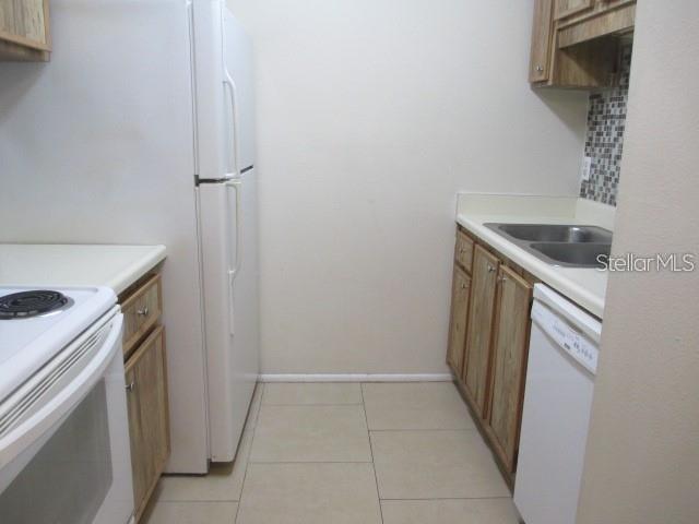A kitchen features a white refrigerator, a stove, wooden cabinets, and a dishwasher — 14227 SHADOW MOSS LANE UNIT 102, TAMPA, FL