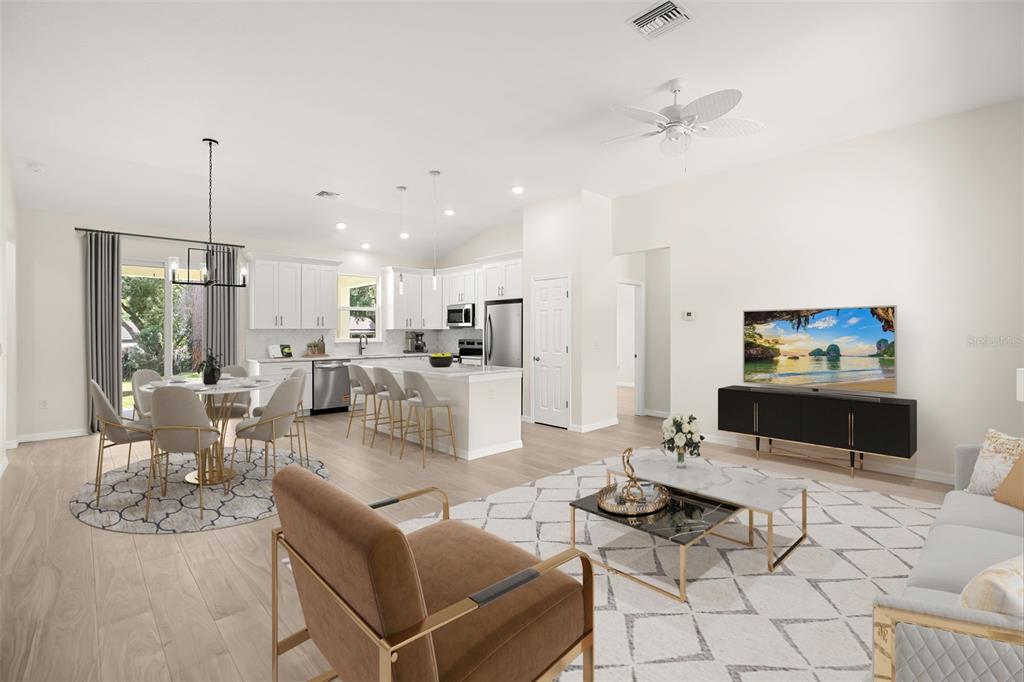 An open-concept living room and kitchen featuring white cabinetry, light wood flooring, and modern furniture — 247 DEBARY DR, DEBARY, FL