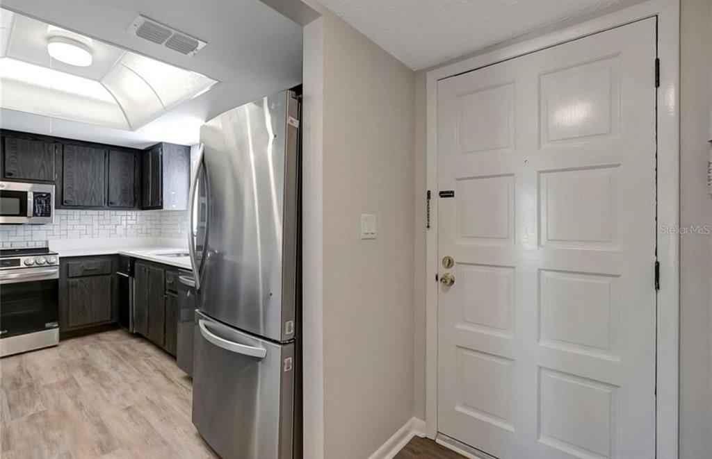 A kitchen with dark cabinets and stainless steel appliances sits next to a white door — 7020 COGNAC DRIVE UNIT 3, NEW PORT RICHEY, FL