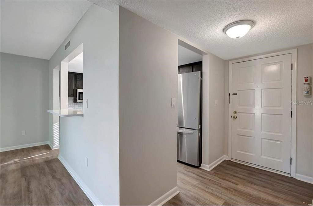 An entryway with wood-look flooring leads to a kitchen with stainless steel appliances — 7020 COGNAC DRIVE UNIT 3, NEW PORT RICHEY, FL