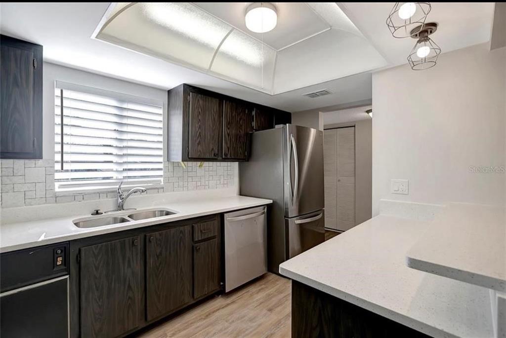 A kitchen with dark wood cabinets, white countertops, stainless steel appliances, and a tray ceiling — 7020 COGNAC DRIVE UNIT 3, NEW PORT RICHEY, FL