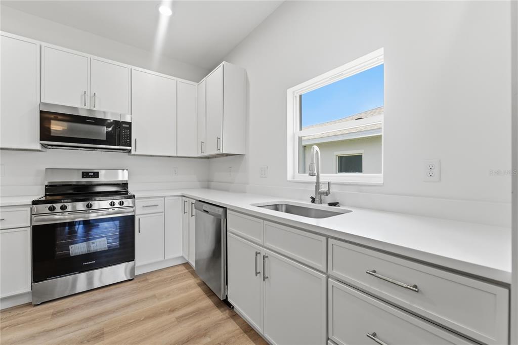 A modern kitchen features white cabinetry, stainless steel appliances, and a window above the sink — 1324 MARSHALL DRIVE, LEESBURG, FL