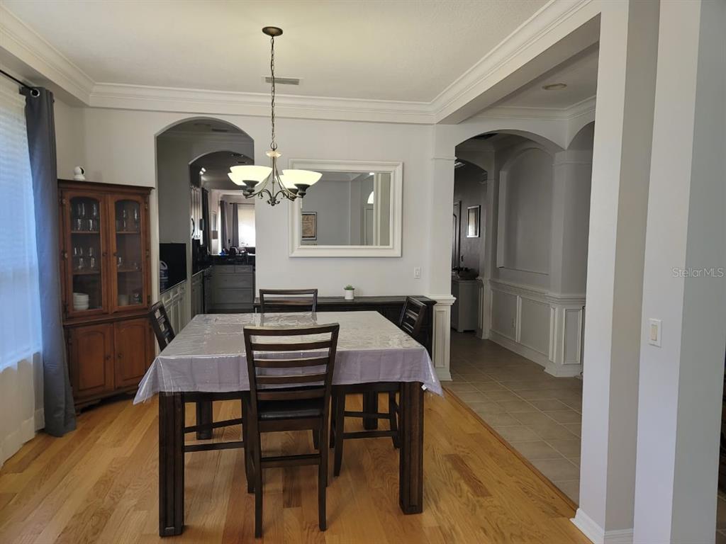 A dining room features a wooden table, chairs, a hutch, and a chandelier on hardwood floors — 7011 NOBLETON DRIVE, WINDERMERE, FL