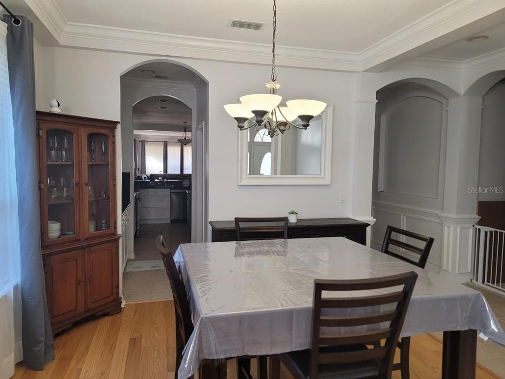 A dining room with a square table, wooden chairs, a china cabinet, and a chandelier — 7011 NOBLETON DRIVE, WINDERMERE, FL