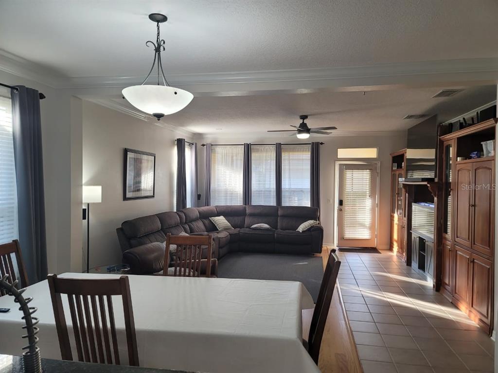 A living room with a sectional sofa, dining table, and tile flooring near a glass door — 7011 NOBLETON DRIVE, WINDERMERE, FL