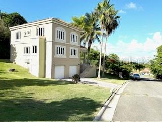 A two-story beige house with a two-car garage sits on a grassy hill — 56 HARBOUR LIGHTS ESTATES EXTENSION UNIT 56, HUMACAO, PR