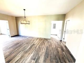 An empty room with wood-look flooring, a modern chandelier, and doorways leading to other areas — 56 HARBOUR LIGHTS ESTATES EXTENSION UNIT 56, HUMACAO, PR