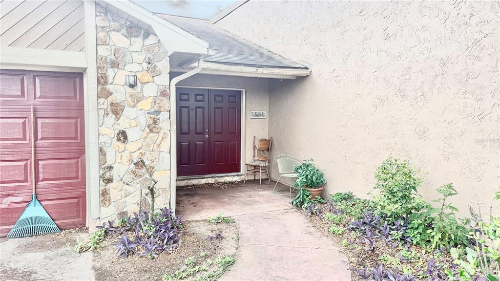 The exterior view shows a house entrance with a stone facade, double doors, and landscaping — 1406 MEADOW DRIVE NE, WINTER HAVEN, FL