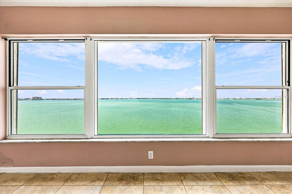 A room with beige tile flooring and a large three-pane window overlooking the ocean — 6020 SHORE BOULEVARD S UNIT 1002, GULFPORT, FL