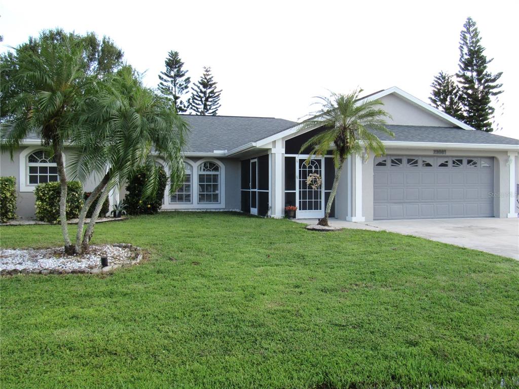 A single-story house with a gray exterior, a two-car garage, and a front lawn — 23081 AMBASSADOR AVENUE, PORT CHARLOTTE, FL