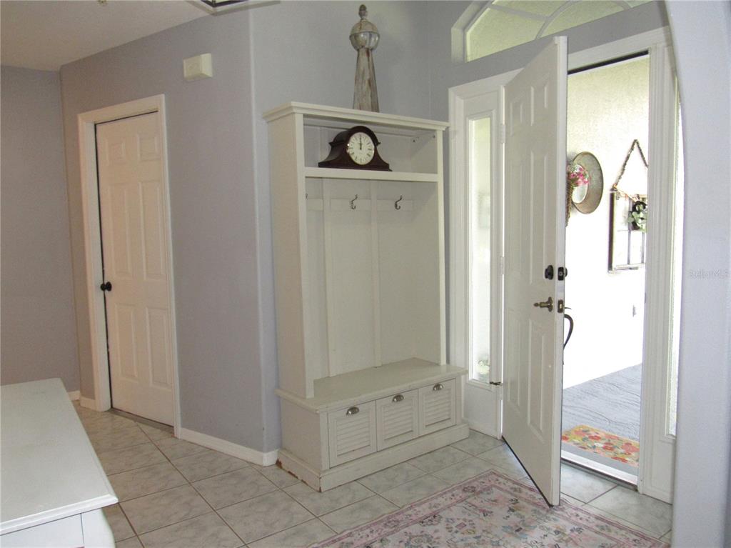 An entryway features a white hall tree, tiled floors, and an open front door — 23081 AMBASSADOR AVENUE, PORT CHARLOTTE, FL