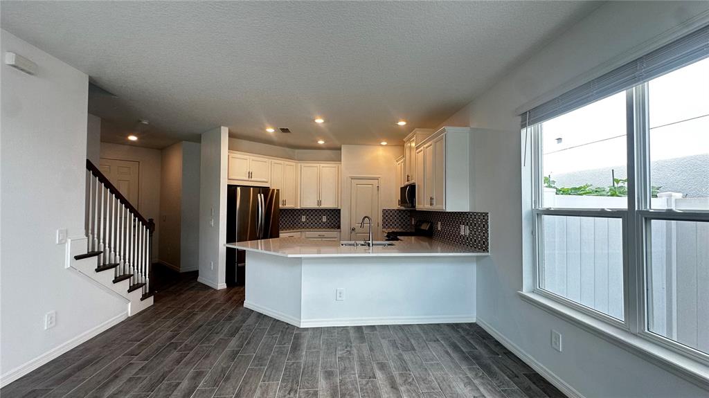 A kitchen with white cabinets, a peninsula, and dark wood-look flooring — 1025 PANDO LOOP, ORLANDO, FL