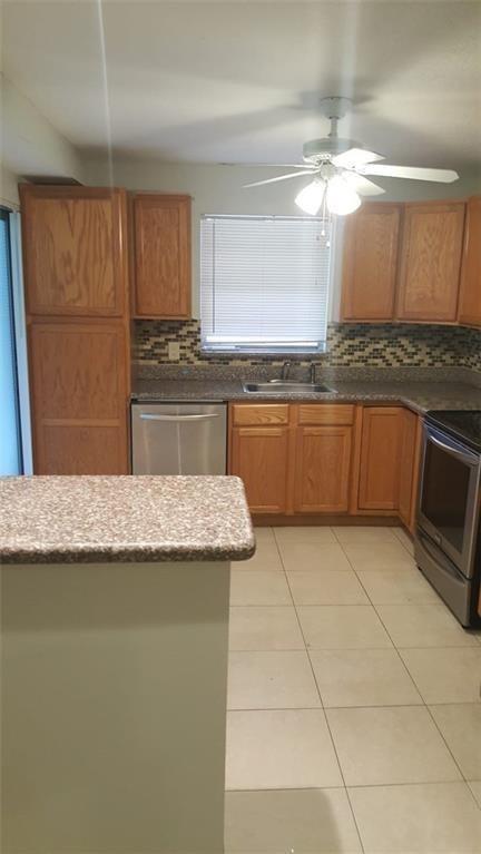 A kitchen features light wood cabinets, a tiled backsplash, stainless steel appliances, and tile flooring — 180 NE 12th Avenue # 17a, Hallandale Beach FL 33009, HALLANDALE BEACH, FL