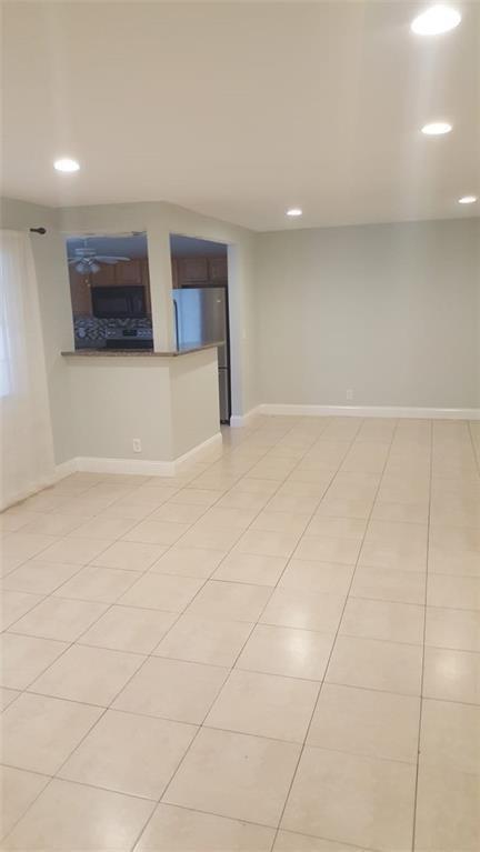 An open-concept living area features light-colored tile flooring and a pass-through to the kitchen — 180 NE 12th Avenue # 17a, Hallandale Beach FL 33009, HALLANDALE BEACH, FL