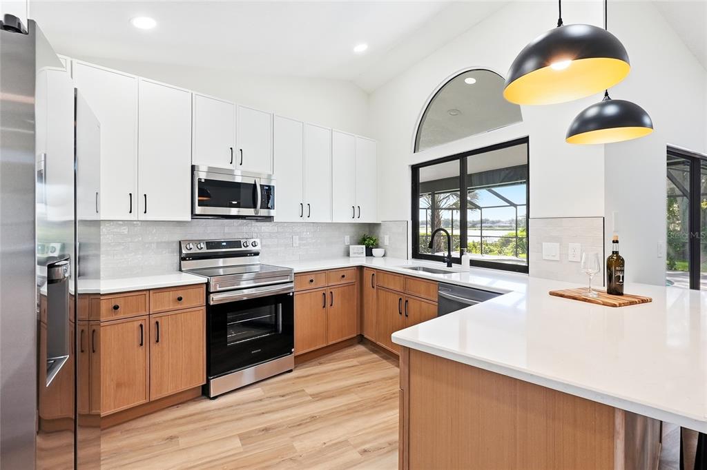 A kitchen features white upper cabinets, wood lower cabinets, white countertops, and a large window — 2889 HAMMOCK DRIVE, PLANT CITY, FL
