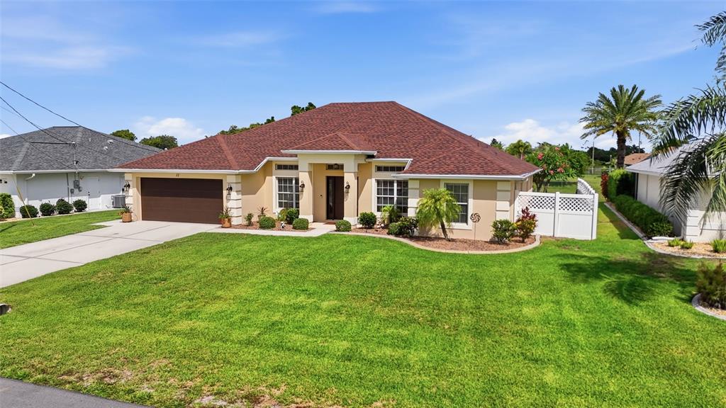 A single-story house with a brown roof, tan stucco exterior, and a two-car garage — 11 MEDALIST LANE, ROTONDA WEST, FL