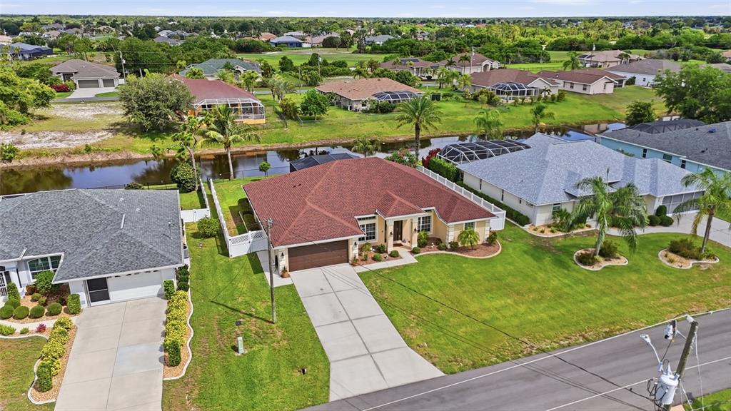 An aerial view shows a suburban house with a red roof, driveway, and canal — 11 MEDALIST LANE, ROTONDA WEST, FL