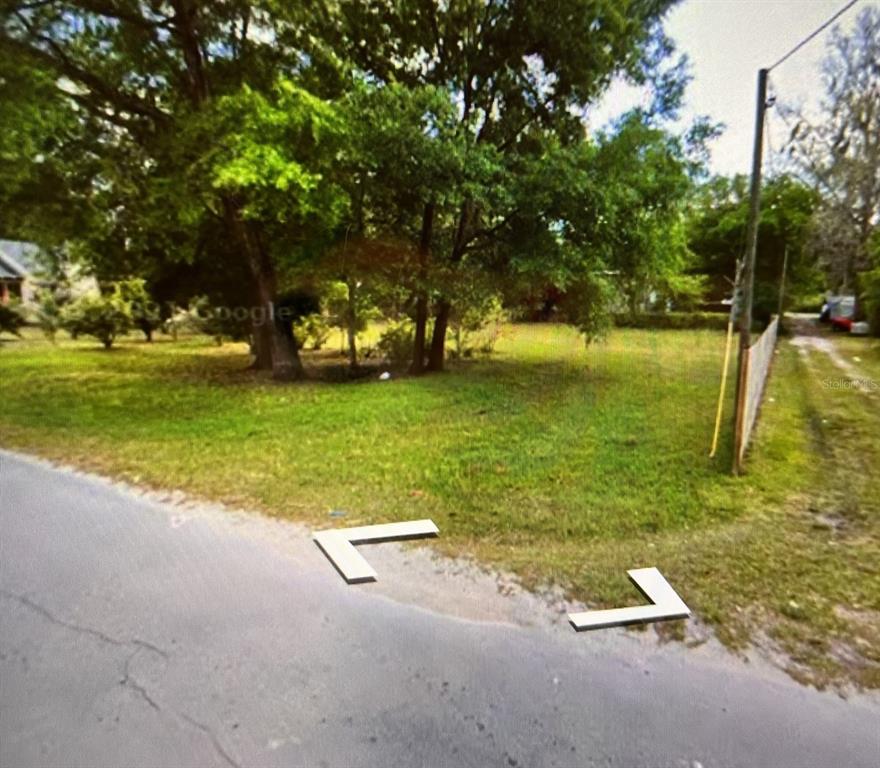 A grassy, tree-filled vacant lot sits adjacent to a paved road and a fence — 0000 SW 134TH AVENUE, ARCHER, FL