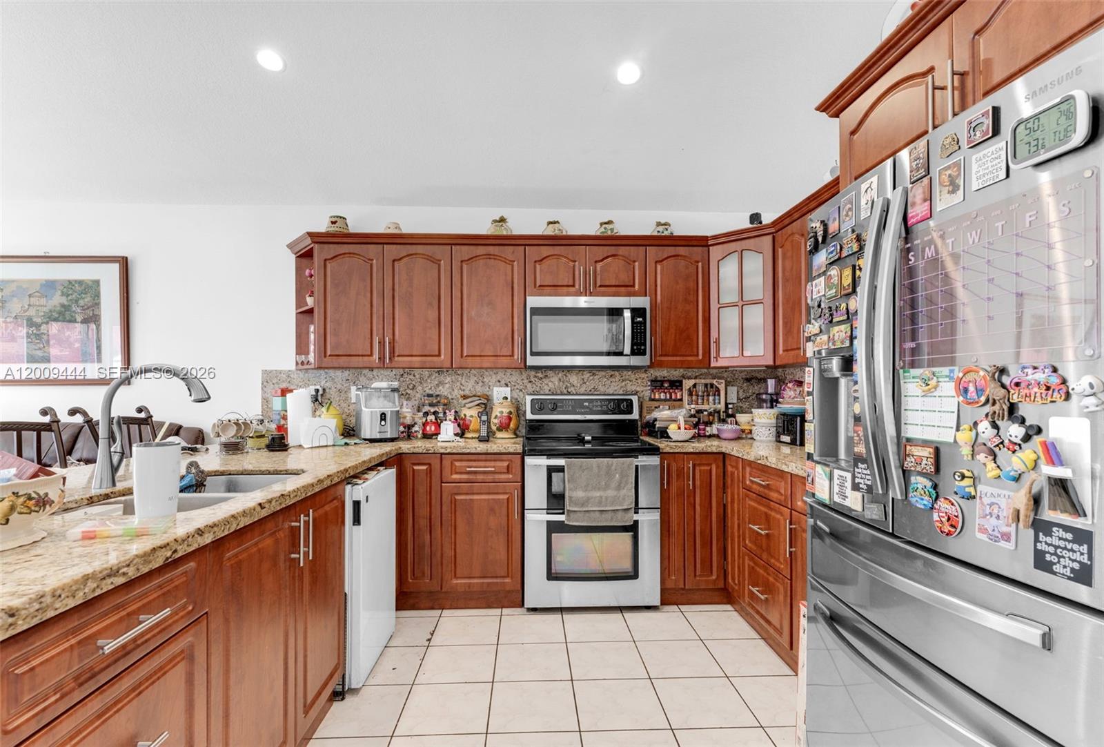 A kitchen features wood cabinets, granite countertops, stainless steel appliances, and a tiled floor — 14240 SW 171st St, Miami FL 33177, MIAMI, FL