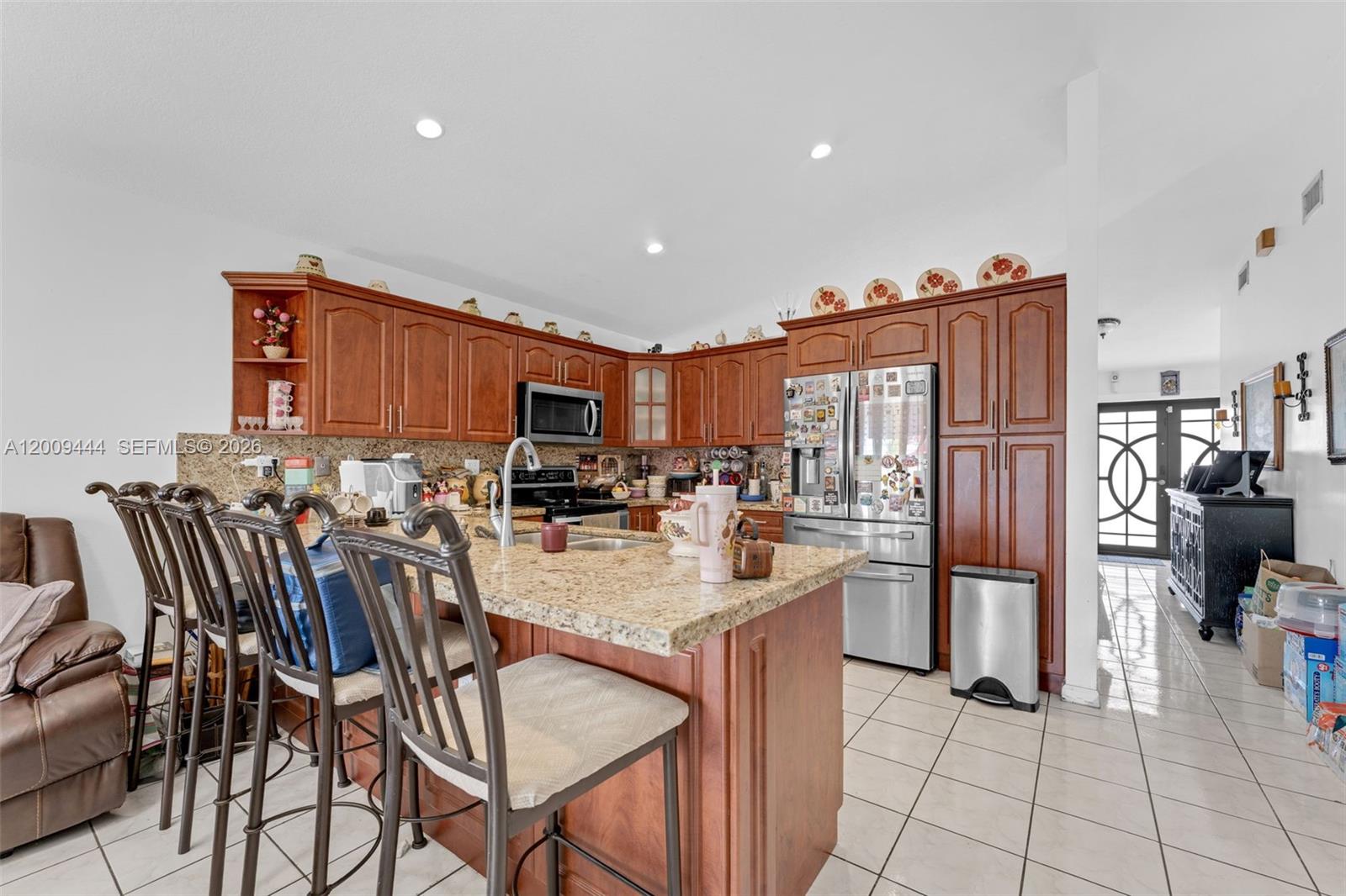 A kitchen features wood cabinets, granite countertops, a center island with seating, and tile flooring — 14240 SW 171st St, Miami FL 33177, MIAMI, FL