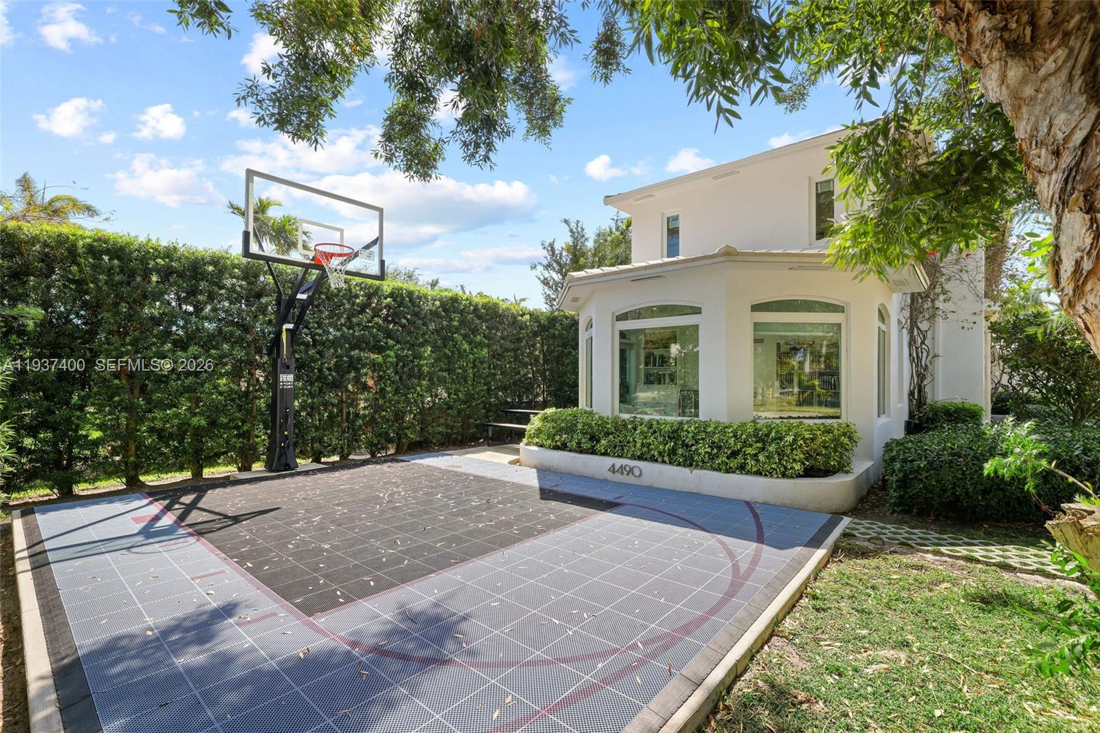 A basketball court with a hoop sits next to a white house with large windows — 4490 Royal Palm Ave, Miami Beach FL 33140, MIAMI BEACH, FL