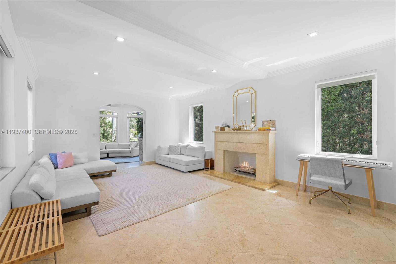 A bright living room features a stone fireplace, light tile floors, and white sectional sofas — 4490 Royal Palm Ave, Miami Beach FL 33140, MIAMI BEACH, FL