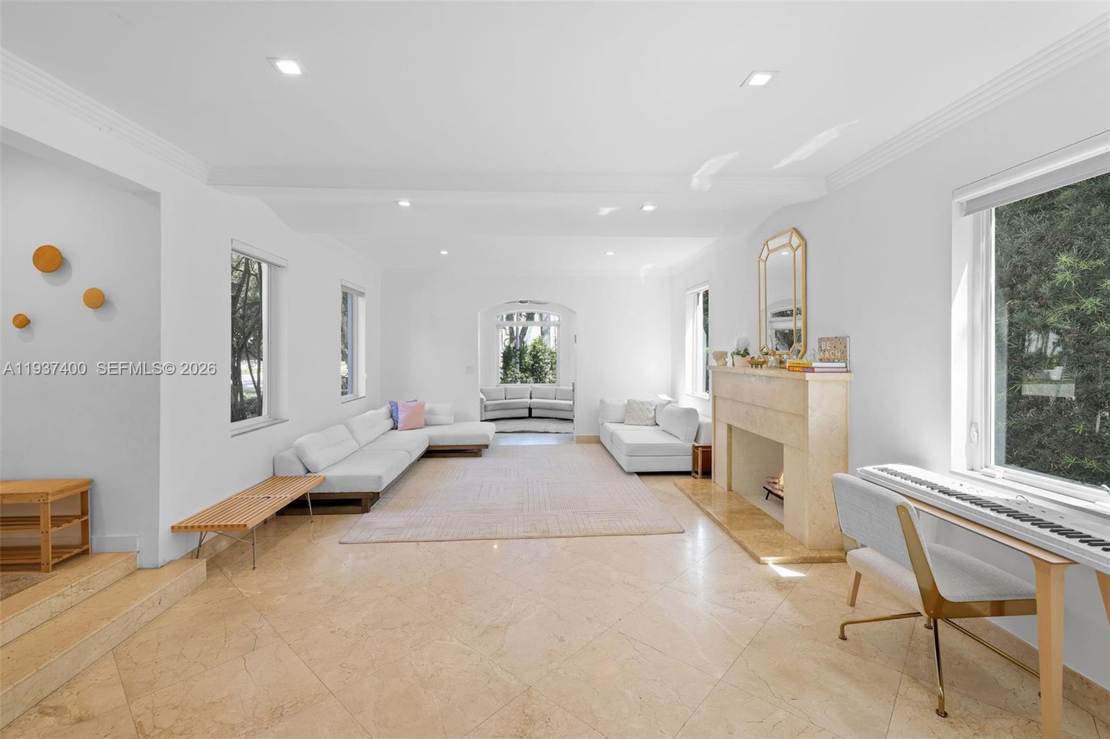 A bright living room features white sofas, a stone fireplace, and light tile flooring — 4490 Royal Palm Ave, Miami Beach FL 33140, MIAMI BEACH, FL