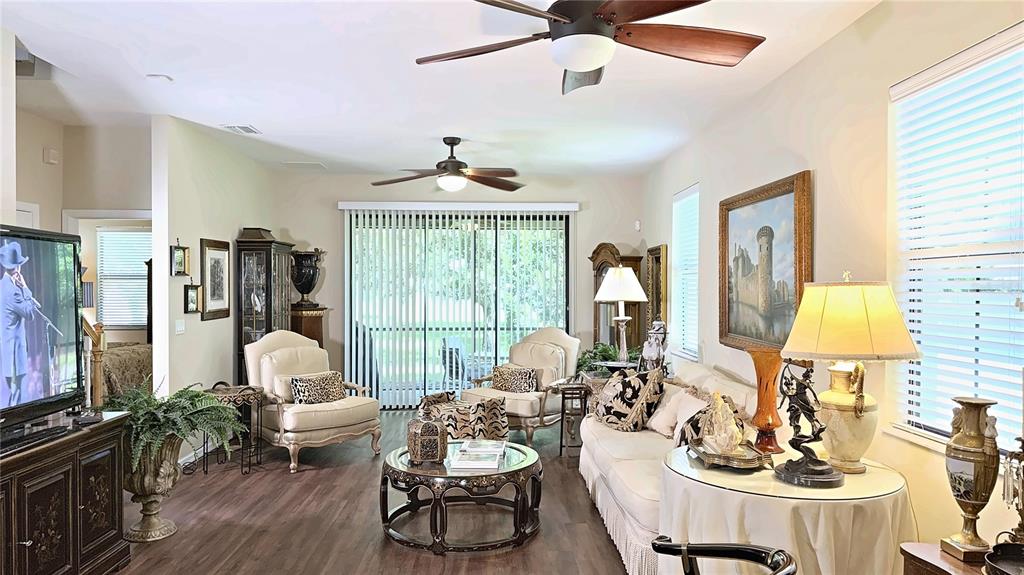 A living room features two ceiling fans, a sofa, armchairs, and a large framed painting — 7974 TASSO COURT, SEMINOLE, FL