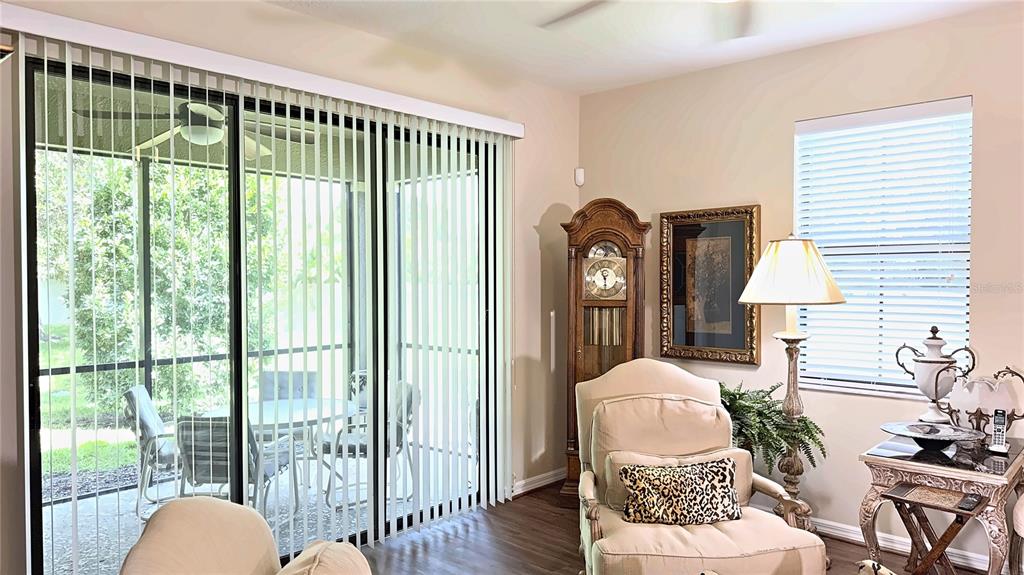 A living room features a grandfather clock, a beige armchair, and sliding glass patio doors — 7974 TASSO COURT, SEMINOLE, FL