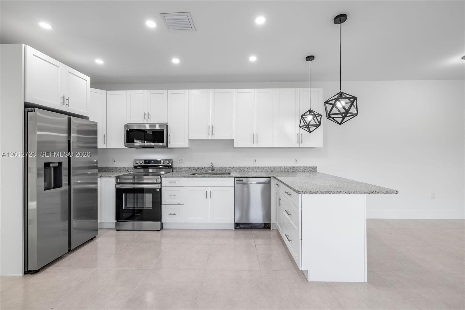 A modern kitchen features white cabinetry, stainless steel appliances, and a granite-topped peninsula — 11238 SW 187th St # 11238, Miami FL 33157, MIAMI, FL