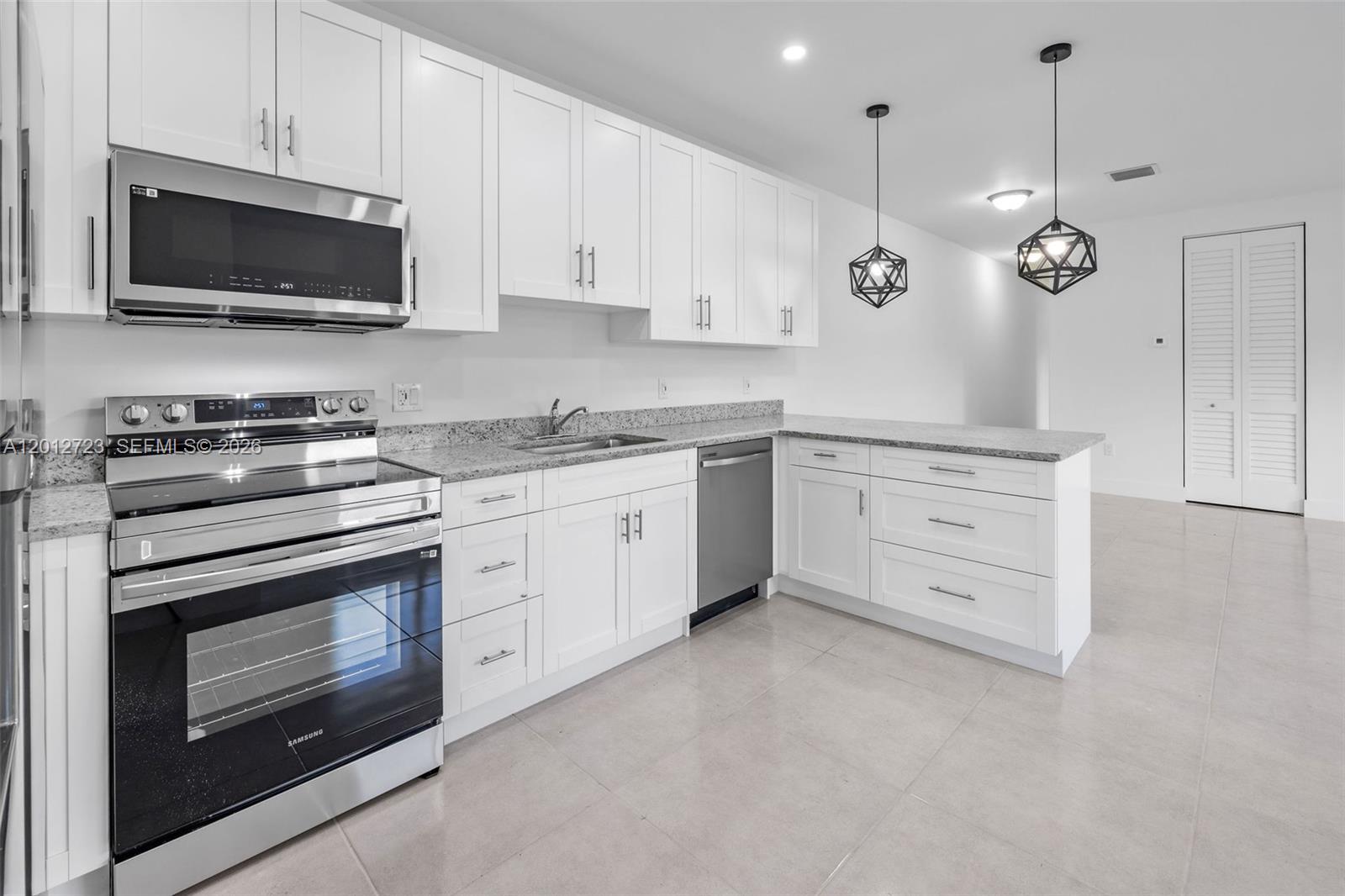 A modern kitchen features white cabinets, granite countertops, stainless steel appliances, and geometric pendant lights — 11238 SW 187th St # 11238, Miami FL 33157, MIAMI, FL