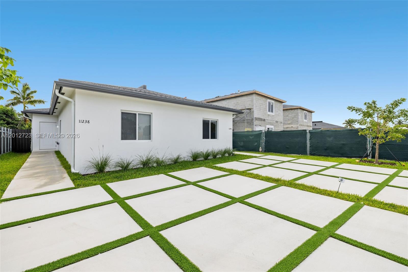 A white house features a grid-patterned concrete driveway with grass strips and a side entrance — 11238 SW 187th St # 11238, Miami FL 33157, MIAMI, FL
