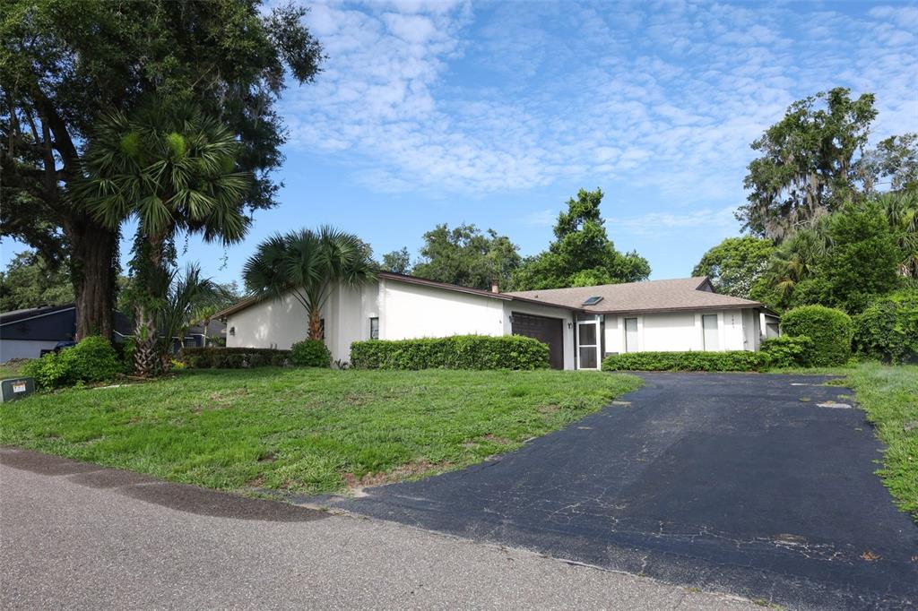 A single-story house with a white exterior, a brown roof, and a paved driveway — 1064 OLD MAGNOLIA COVE DRIVE, APOPKA, FL
