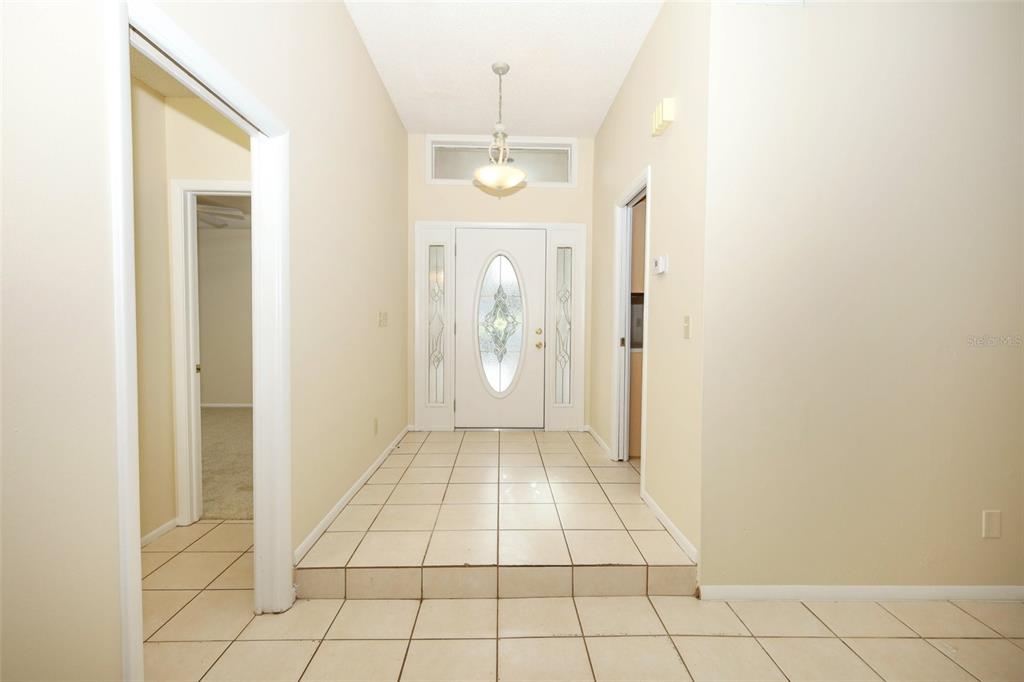 An entryway features a tiled floor, a raised landing, and a white front door — 1064 OLD MAGNOLIA COVE DRIVE, APOPKA, FL