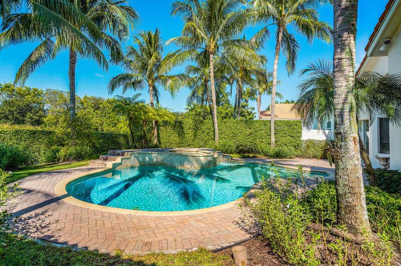 A backyard swimming pool with a raised spa is surrounded by palm trees and landscaping — 14364 Stroller Way, Wellington FL 33414, WELLINGTON, FL