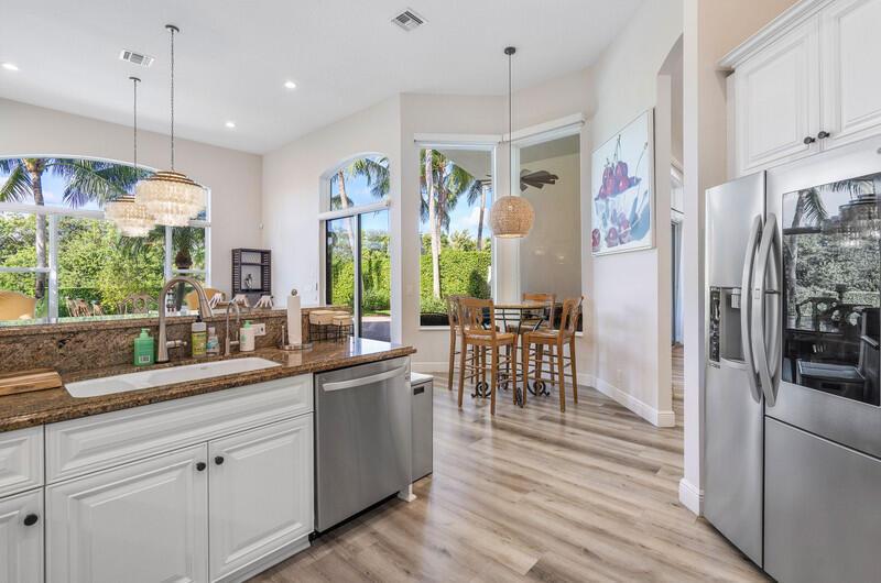A kitchen features white cabinets, granite countertops, stainless steel appliances, and a dining nook area — 14364 Stroller Way, Wellington FL 33414, WELLINGTON, FL