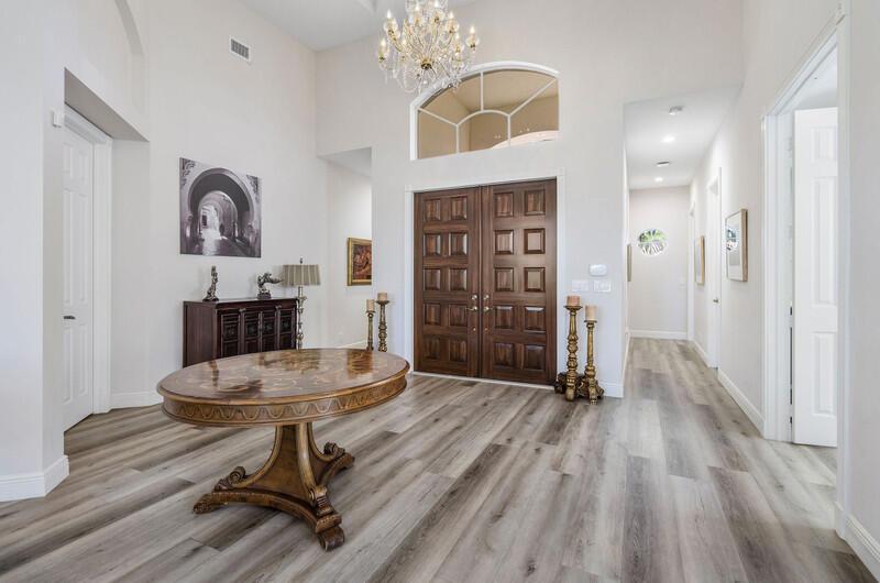 A foyer features a round wooden table, a crystal chandelier, and dark wood double doors — 14364 Stroller Way, Wellington FL 33414, WELLINGTON, FL