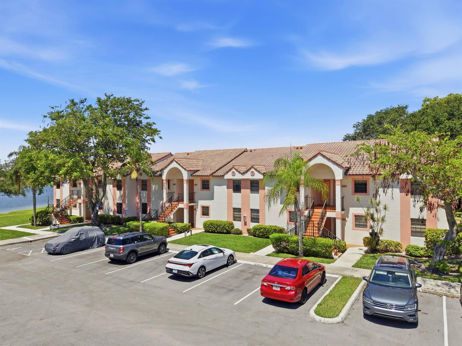 An exterior view of a two-story apartment building with a parking lot in front — 321 Norwood Terrace # N221, Boca Raton FL 33431, BOCA RATON, FL
