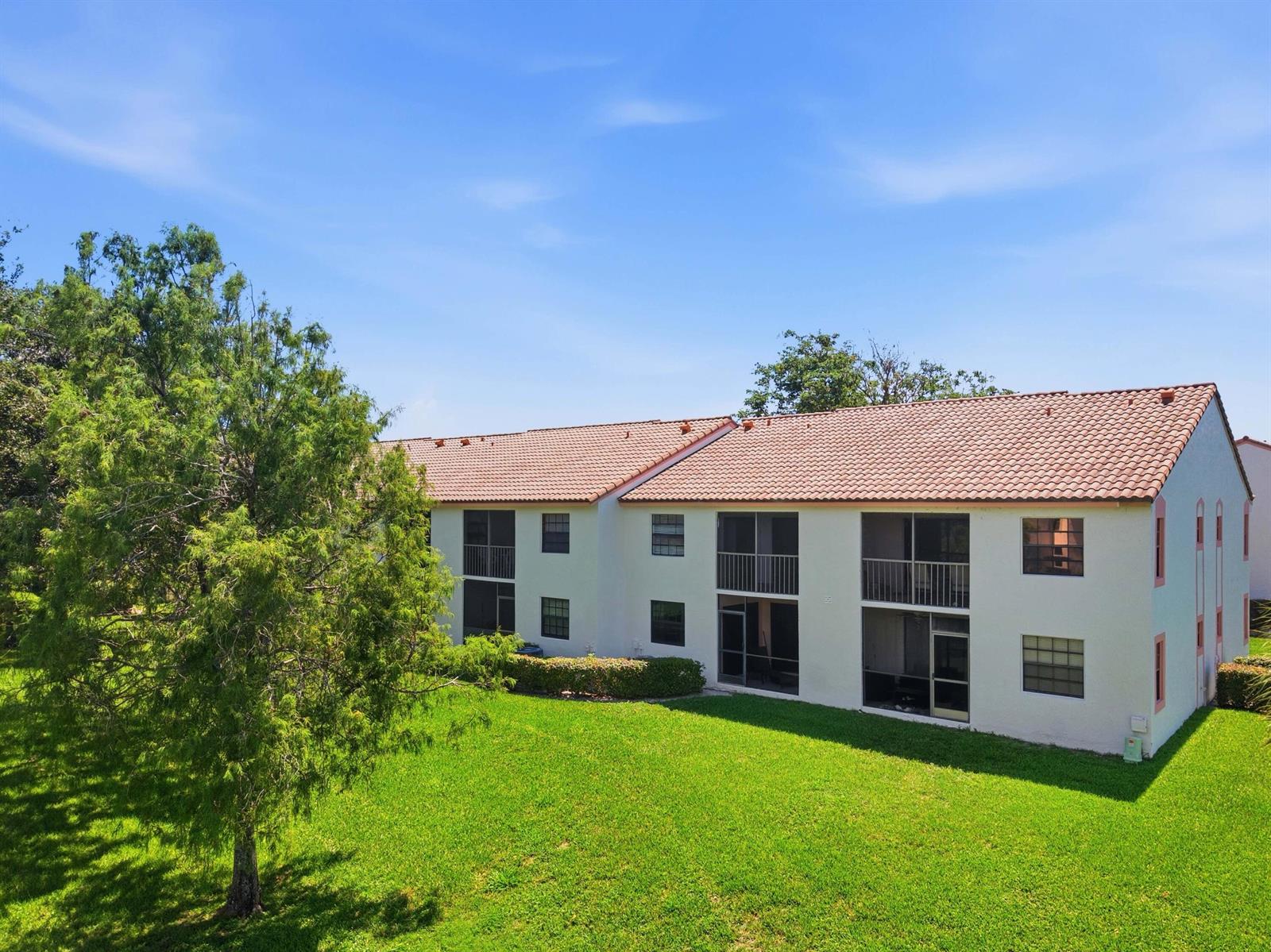 A two-story apartment building with a tiled roof sits beside a large green lawn — 321 Norwood Terrace # N221, Boca Raton FL 33431, BOCA RATON, FL