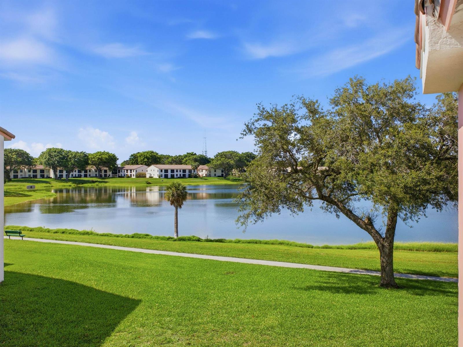 A view of a grassy lawn, a lake, and apartment buildings under a blue sky — 321 Norwood Terrace # N221, Boca Raton FL 33431, BOCA RATON, FL