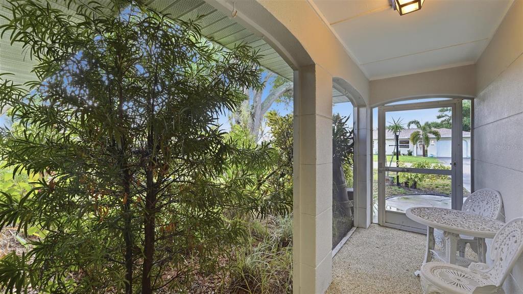 A screened-in porch features a small white bistro set and views of a residential street — 1329 NANTUCKET ROAD, VENICE, FL