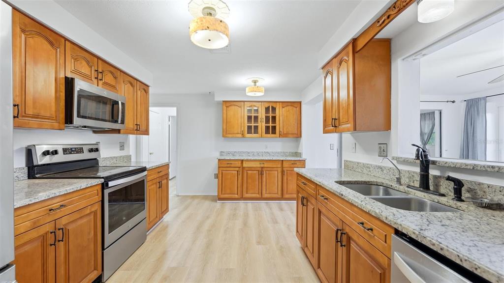 A kitchen with wood cabinets, granite countertops, stainless steel appliances, and light-colored flooring — 1329 NANTUCKET ROAD, VENICE, FL