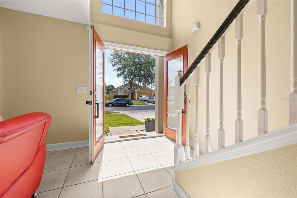 An entryway with tile flooring, a staircase with white railings, and an open front door — 5253 SUNSET CANYON DRIVE, KISSIMMEE, FL
