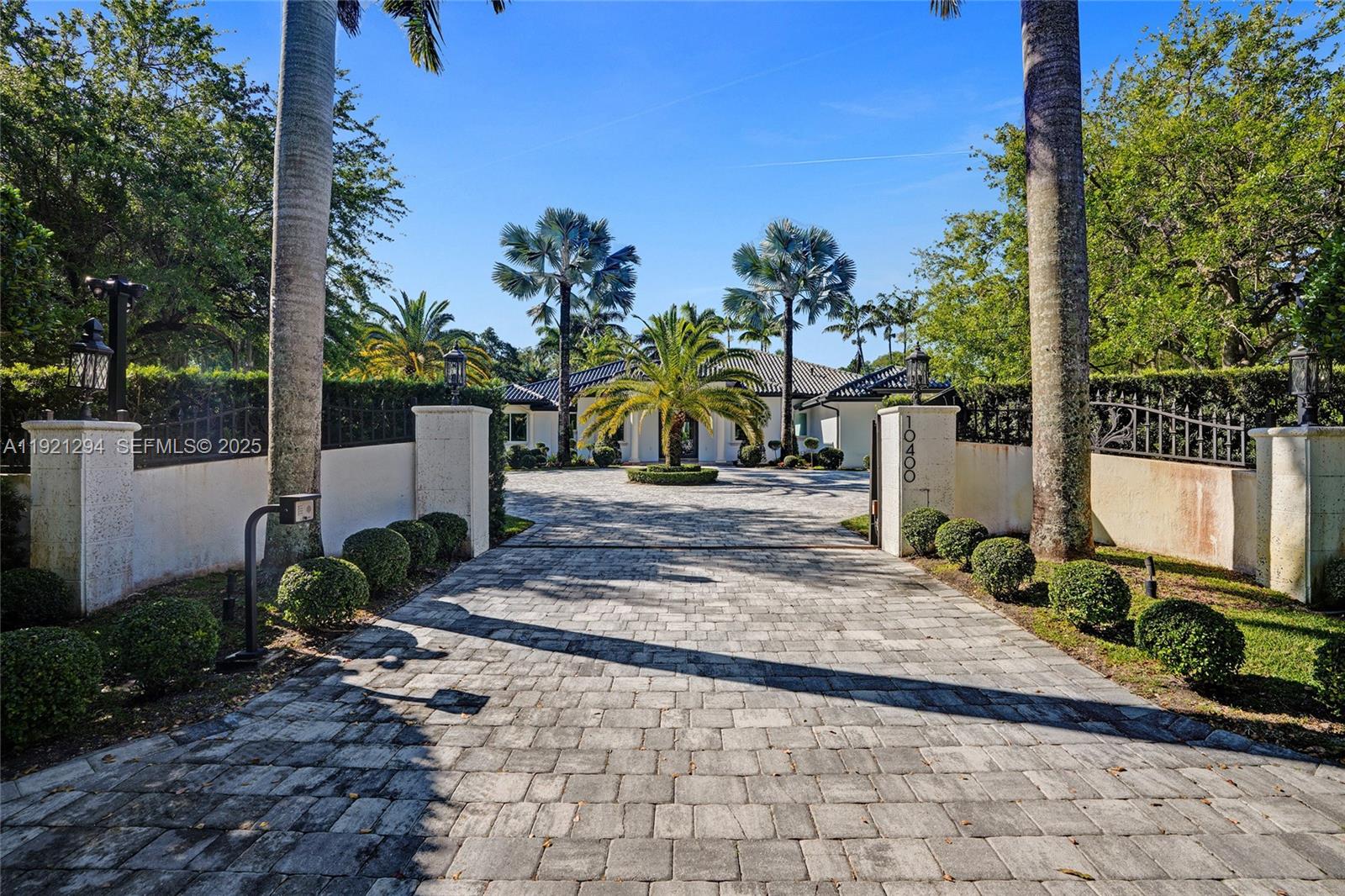 A paved driveway leads through a gated entrance to a house surrounded by palm trees — 10400 SW 62nd St, Miami FL 33173, MIAMI, FL