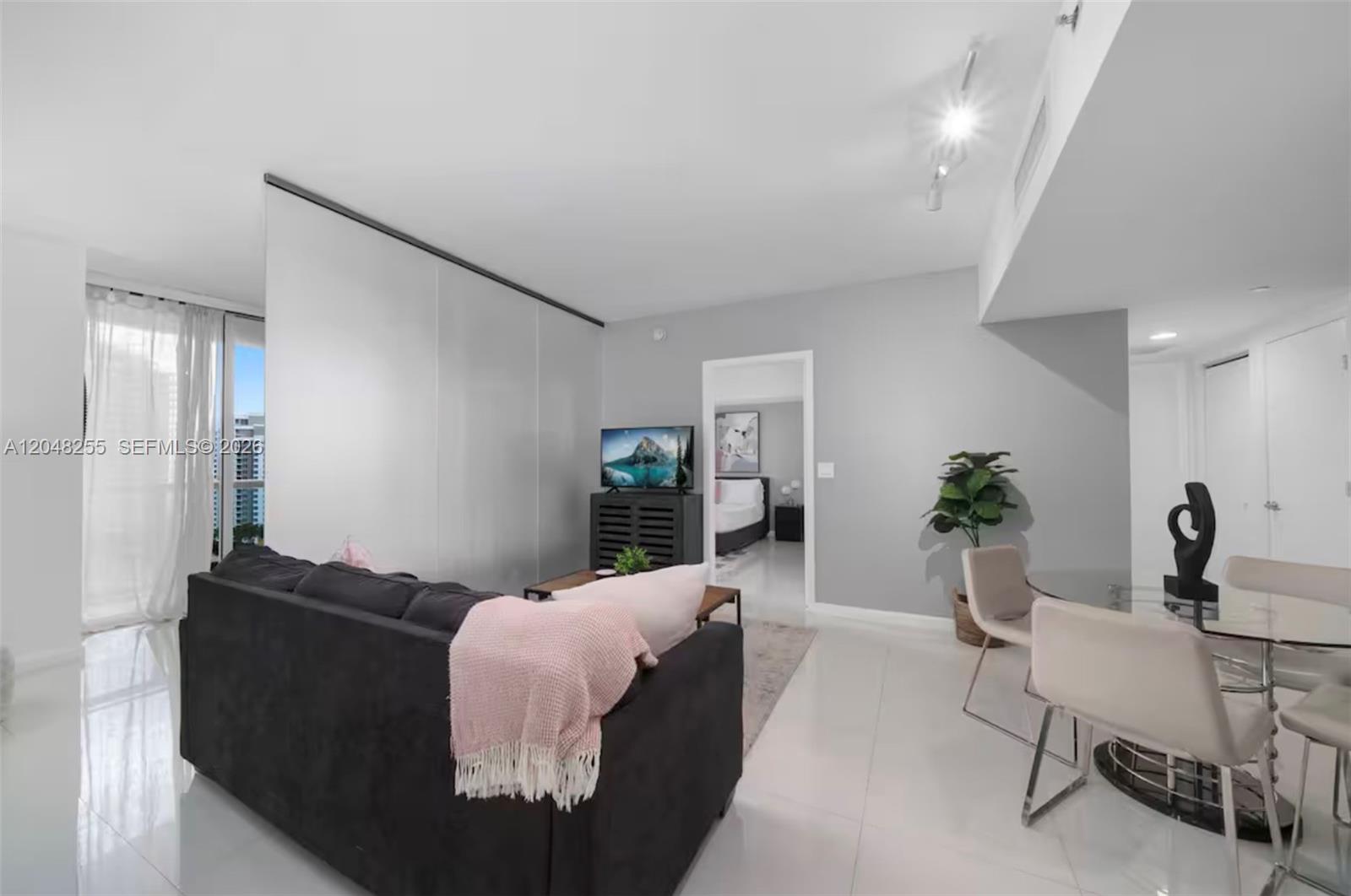 A living room with a dark sofa, dining area, and a view of high-rise buildings — 485 Brickell Ave # 1901, Miami FL 33131, MIAMI, FL