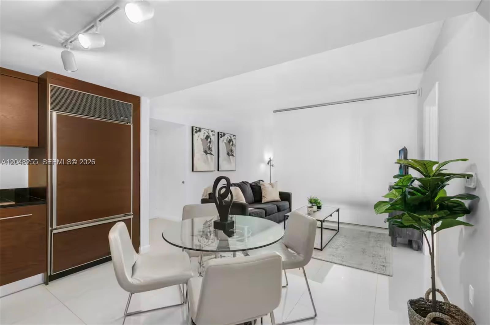 A modern open-concept living and dining area features a glass table, sofa, and wood cabinetry — 485 Brickell Ave # 1901, Miami FL 33131, MIAMI, FL