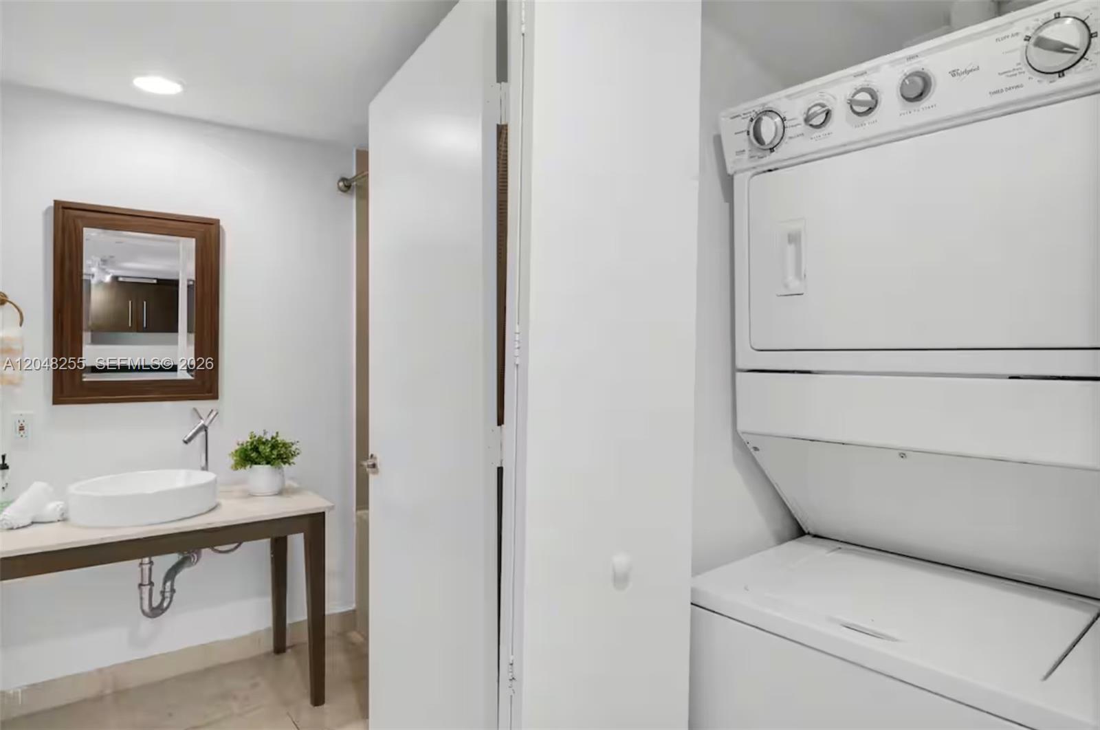 A bathroom with a vessel sink vanity, a mirror, and a stacked washer and dryer — 485 Brickell Ave # 1901, Miami FL 33131, MIAMI, FL