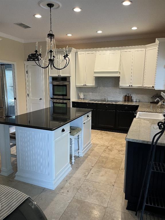 A kitchen features a black-topped island, white upper cabinets, black lower cabinets, and tile flooring — 5879 LAKE MELROSE DRIVE, ORLANDO, FL