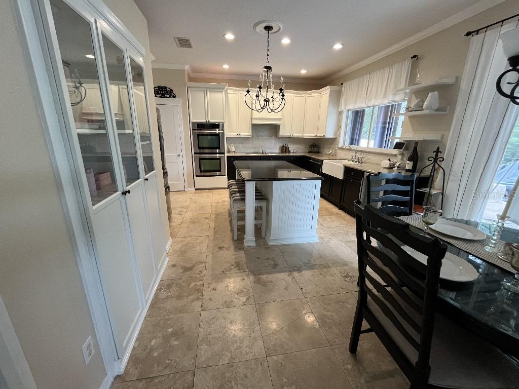 A kitchen features white upper cabinets, dark lower cabinets, a central island, and tile flooring — 5879 LAKE MELROSE DRIVE, ORLANDO, FL