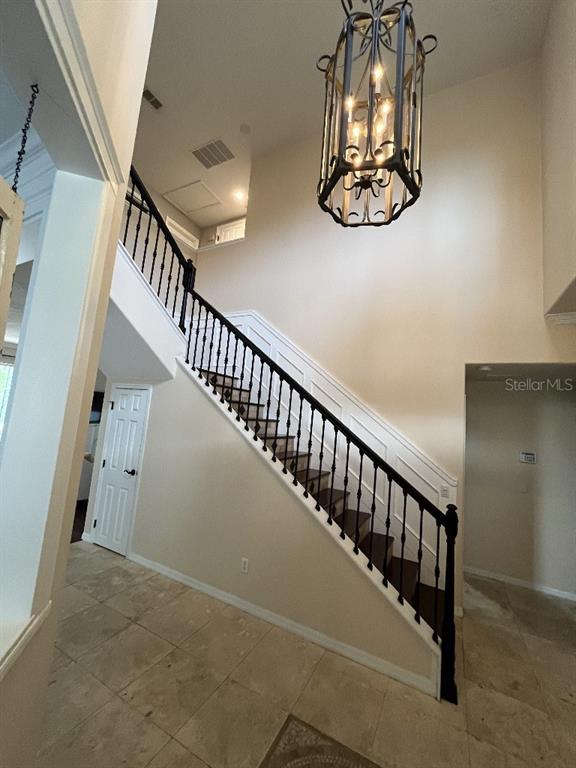 A foyer features a staircase with black railings, tile flooring, and a hanging lantern chandelier — 5879 LAKE MELROSE DRIVE, ORLANDO, FL